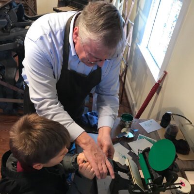 Walton with a young homeschooler printing a bookmark on the Kesley Press.