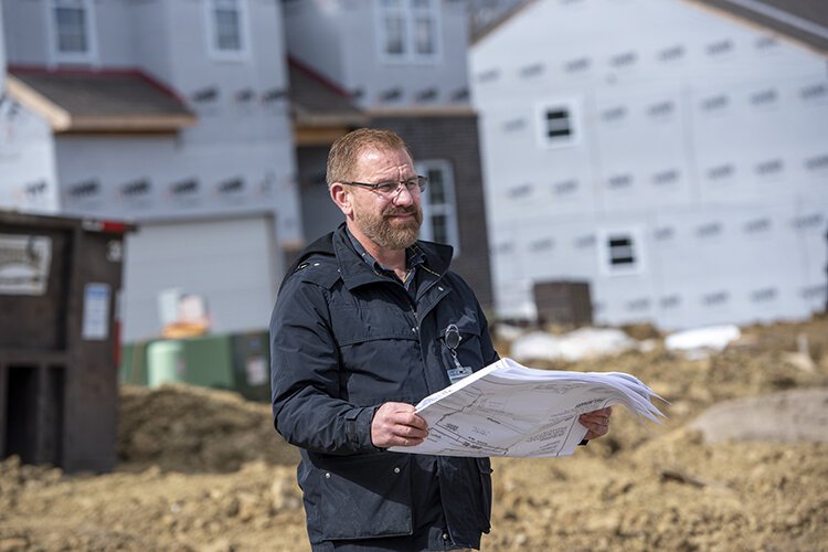 Forest Park Community Development Director Chris Anderson looks over plans for a new residential development, seen behind him, that has been many years in the making. 