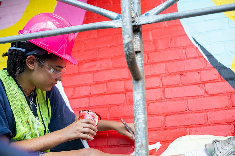 An ArtWorks apprentice works on the "Hear Us Out" mural in Avondale.